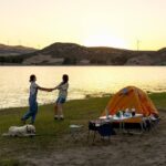 Travelers enjoying a coastal camping trip in Khasab with tents near the beach and scenic mountain views